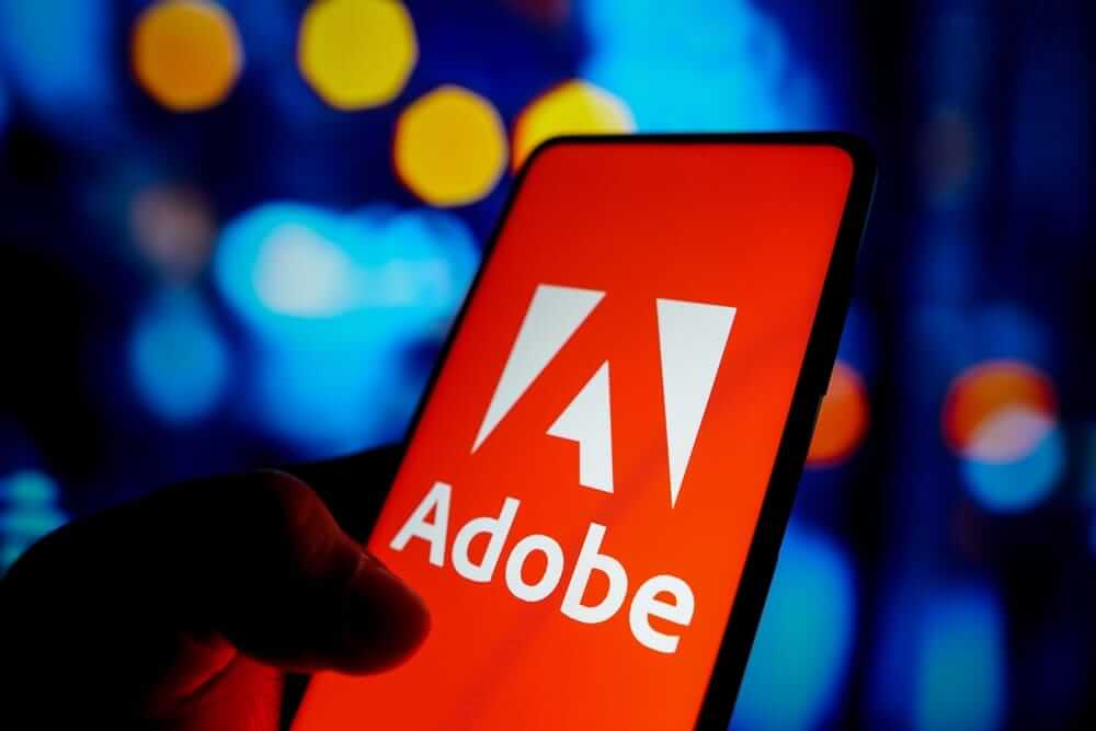 Adobe Inc logo on phone with festive background-by rafapress via Shutterstock